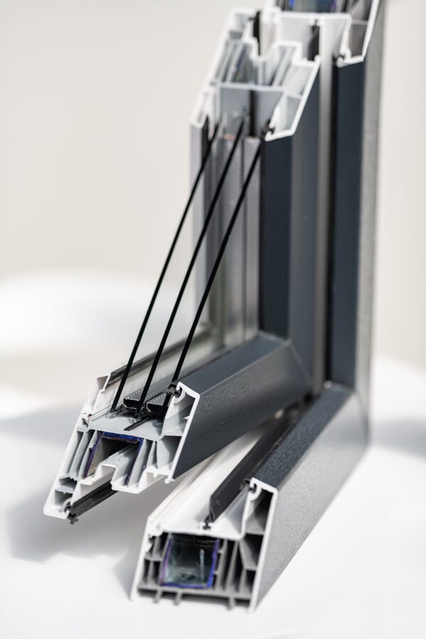 A cutaway cross-section sample of a grey uPVC double-glazed window frame showing the internal chambers and glazing