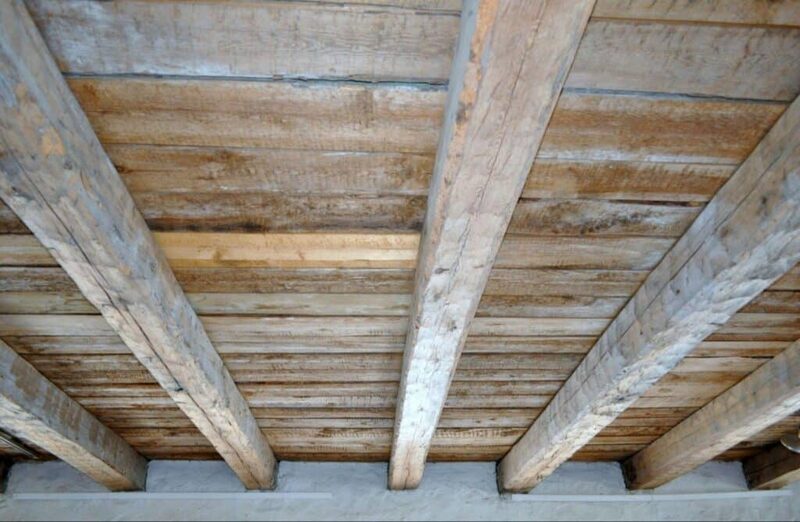 Exposed wooden floor joists and floorboards viewed from below in a room