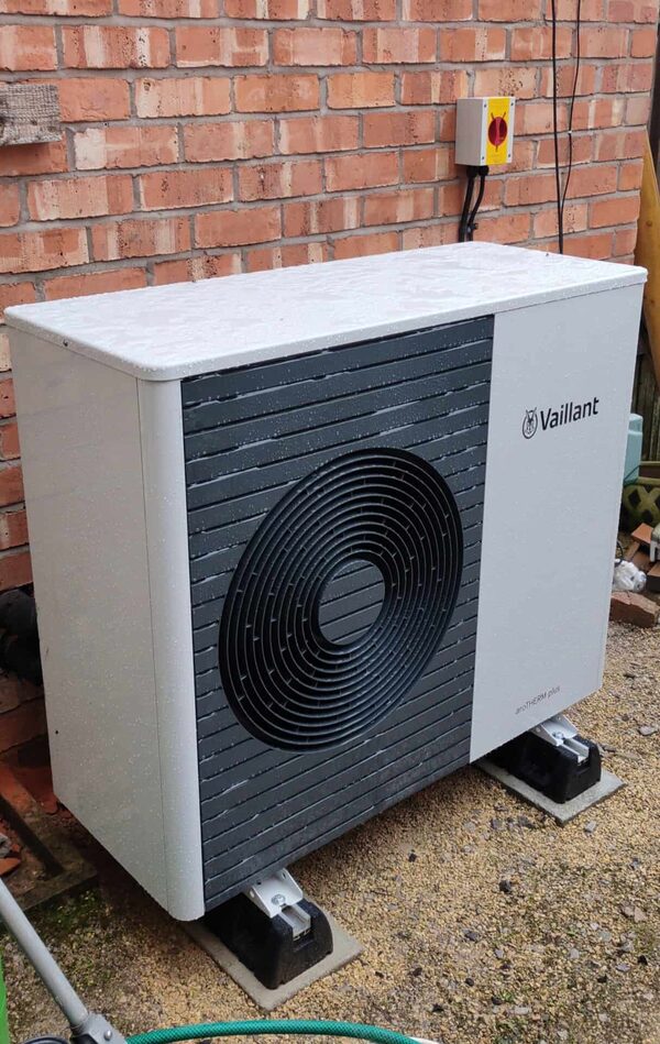A Vaillant air source heat pump unit installed outside against a brick house wall