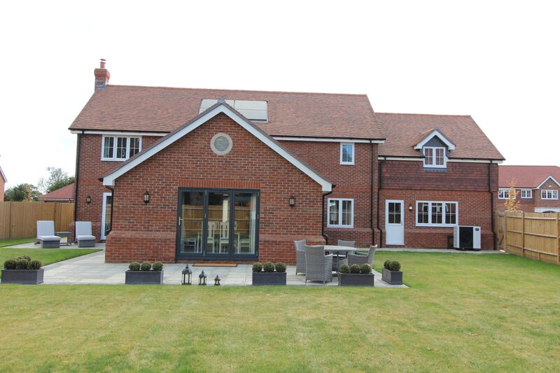 A new brick detached house with an air source heat pump unit beside the rear wall and a solar panel on the roof