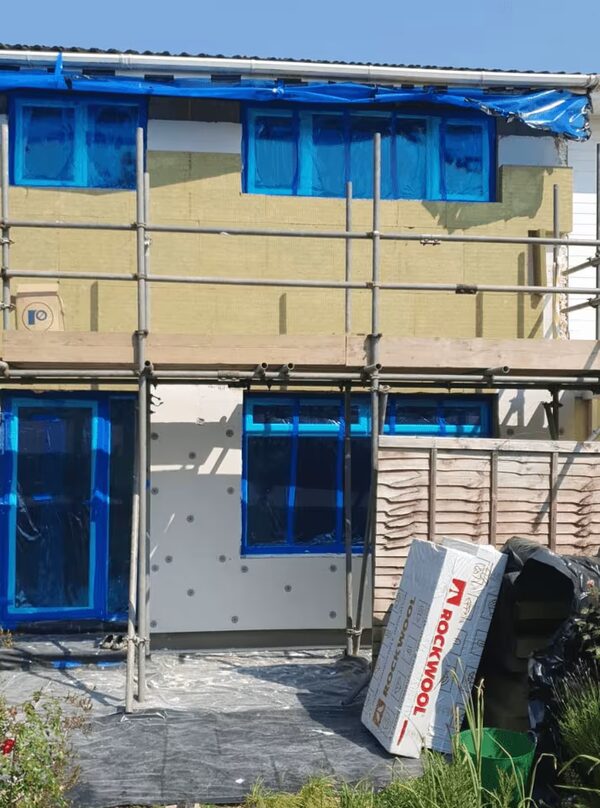 A house undergoing external solid wall insulation, with Rockwool insulation boards fitted and scaffolding around the property