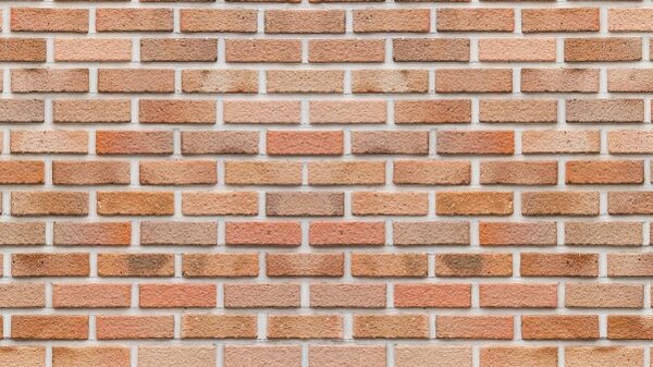 A close-up of a red and orange brick wall laid in a stretcher bond pattern, illustrating cavity wall brickwork.