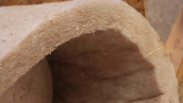 A close-up of a roll of pale pink natural fibre insulation material