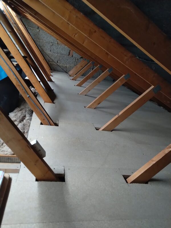 A loft with new chipboard floorboards fitted between the roof rafters, with some insulation visible at the side