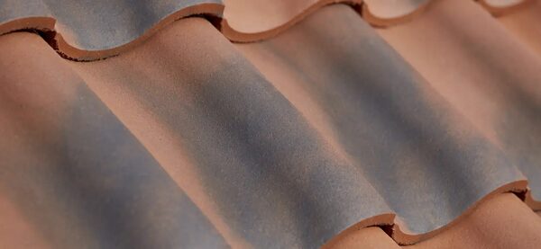 A close-up of terracotta clay pantile roof tiles laid in overlapping rows