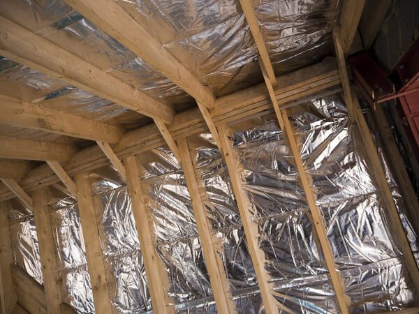 Reflective multifoil insulation fitted between timber rafters in a loft roof