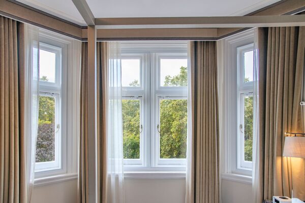 A bay window with white secondary glazing panels fitted behind the primary windows in a curtained room
