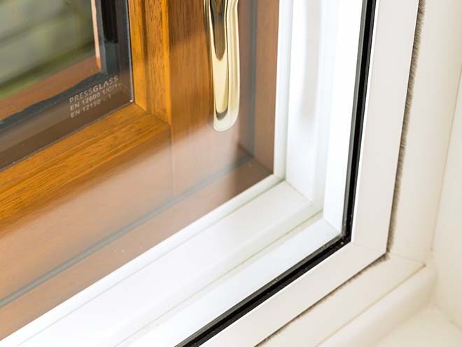 Close-up of a secondary glazing panel fitted inside a wooden-framed window with a brass handle