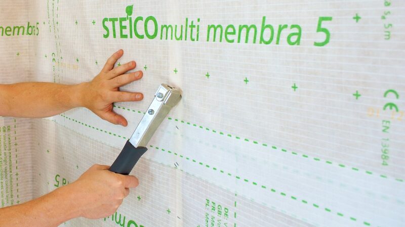 A person stapling Steico multi membra 5 vapour-control membrane to a wall during installation