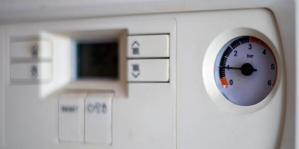 A close-up of a white boiler's control panel with a pressure gauge reading about 1 bar
