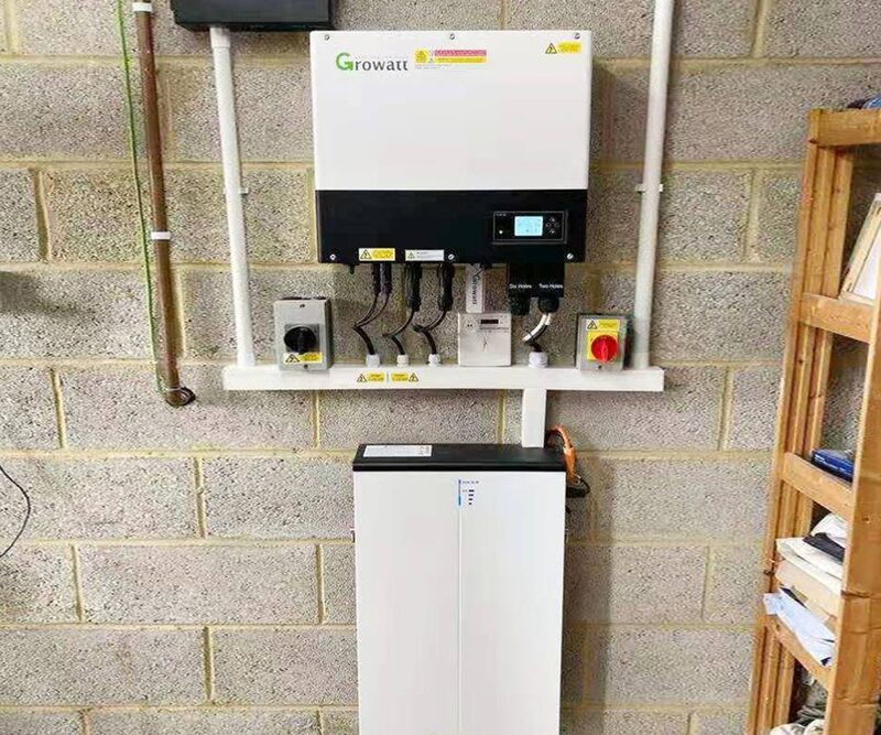 A Growatt SPH6000 hybrid inverter and battery storage unit installed on a brick wall in a garage or utility space