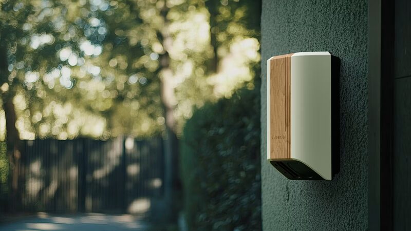 A wall-mounted home EV charger with a wood-effect front panel installed on an exterior house wall