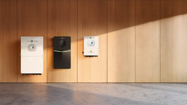 Three Sunsynk solar inverters mounted on a wooden panel wall