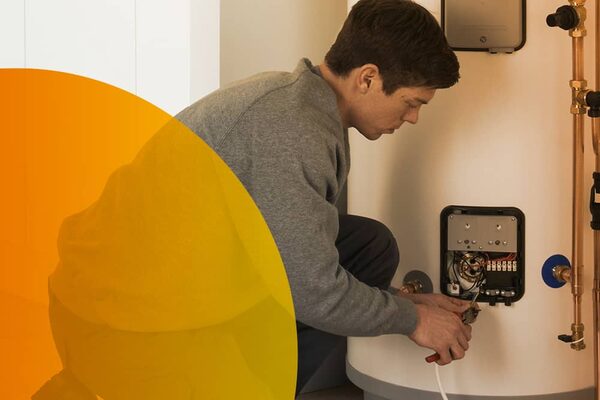 An engineer working on the wiring of a Megaflo hot water cylinder in a home airing cupboard