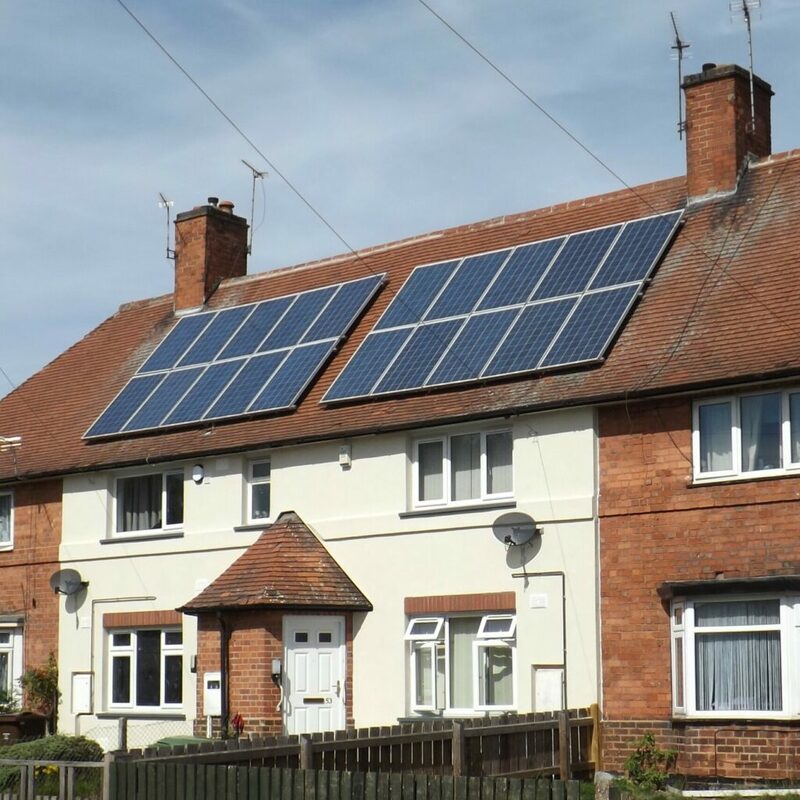 A UK brick semi-detached house with a large array of rooftop solar panels on its tiled roof