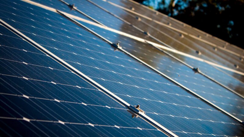 A close-up view of solar panels installed on a roof, angled with mounting rails visible