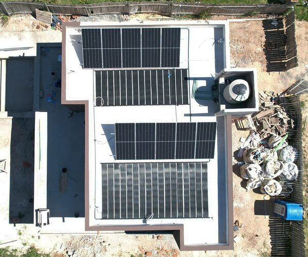 Aerial view of a flat residential roof with several rows of solar panels installed