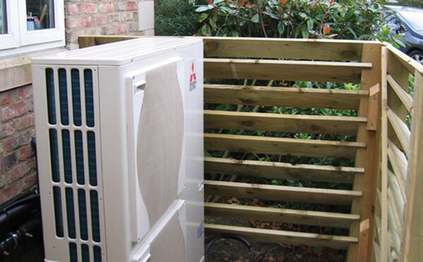 A Mitsubishi Ecodan air source heat pump outdoor unit installed beside a house, screened by a wooden slatted fence