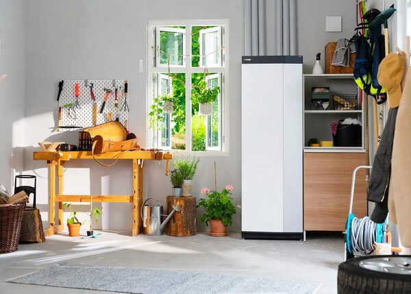 A white NIBE ground source heat pump indoor unit installed in a utility room next to a window, workbench and storage shelves