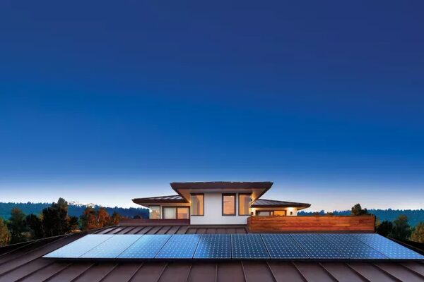 Solar panels installed on the metal roof of a modern house at dusk