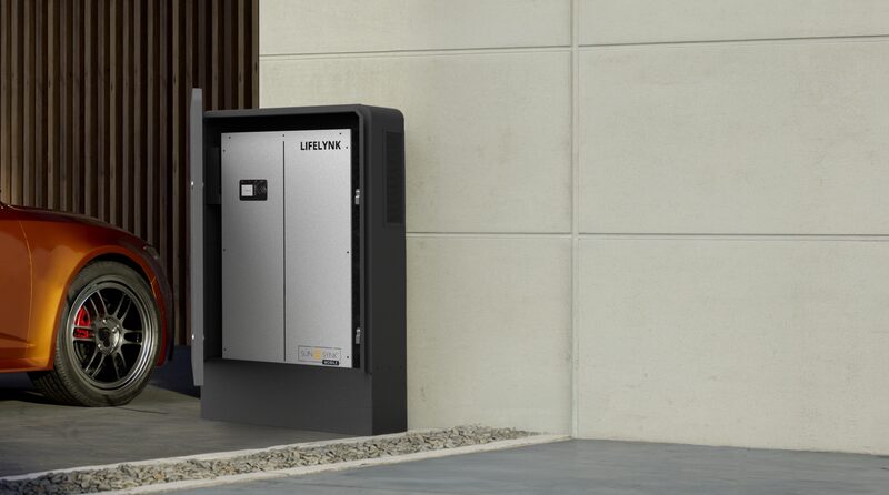 A Sunsynk LYNK all-in-one solar inverter and battery unit mounted outdoors next to a parked car