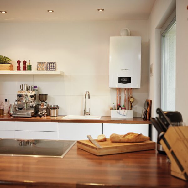 A white Vaillant wall-mounted combi boiler with copper pipework installed in a modern kitchen