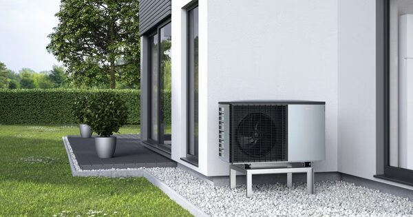 A Viessmann air source heat pump unit installed outside a modern house on a gravel bed beside a patio