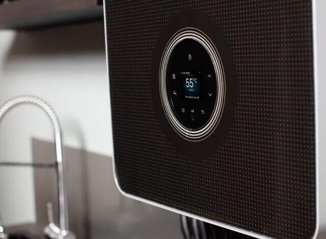 A close-up of a black wall-mounted Worcester Bosch boiler with a circular digital display showing 55°C, installed above a kitchen sink