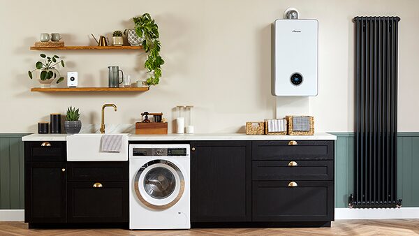 A white Worcester Bosch wall-mounted boiler installed above a utility room counter next to a black column radiator