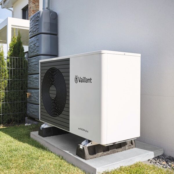 A Vaillant aroTHERM plus air source heat pump installed outside a house next to a rainwater tank