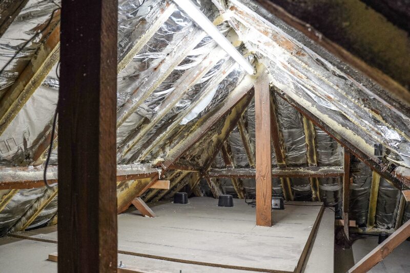 A loft interior with foil-faced reflective insulation fitted between and over the roof rafters and boarded floor