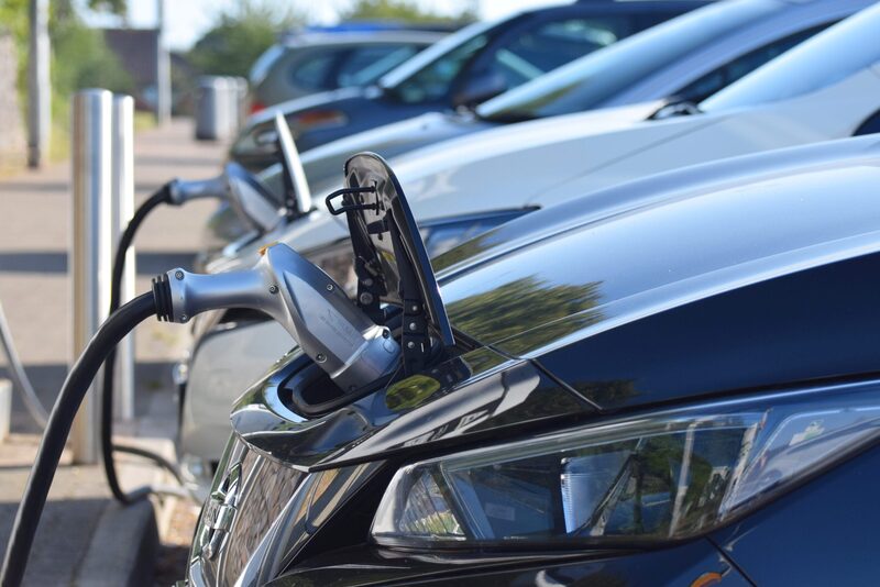 A row of electric cars plugged in with charging cables at a public charging point