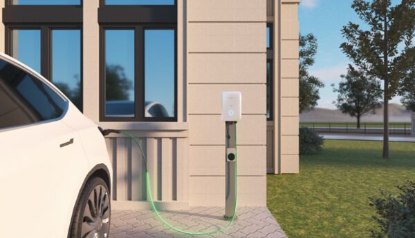 A white electric car charging from a wall-mounted EV charger on a rendered house exterior