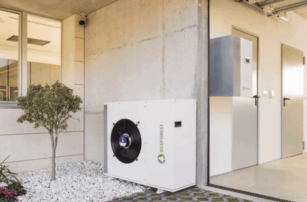 An Ecoforest air source heat pump unit installed outside a modern building wall next to a door