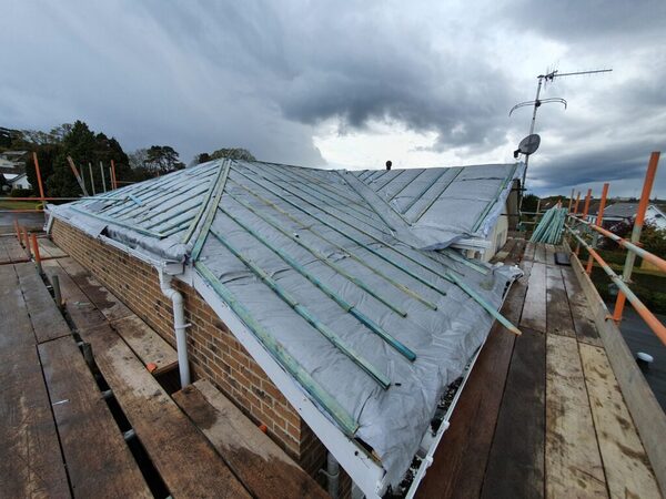 A house roof under renovation, covered with silver foil insulation and battens, seen from scaffolding