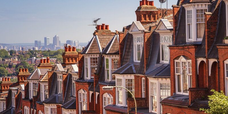 A row of red-brick Victorian terraced houses with the London skyline in the distance
