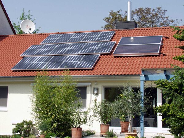 Photovoltaic panels and a solar thermal collector installed on the tiled roof of a house