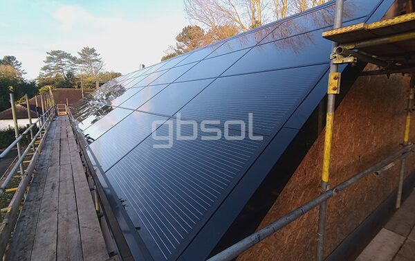 A large in-roof solar panel array being installed on a house roof, surrounded by scaffolding