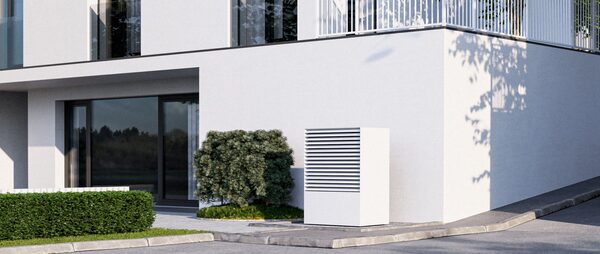 A white air source heat pump unit installed outside a modern white-rendered residential building