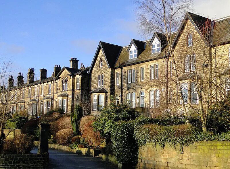 A row of traditional stone terraced houses on a sunny street in the UK