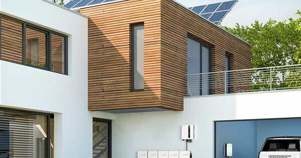 A modern house with rooftop solar panels, a wall-mounted battery unit and an EV charger in the garage