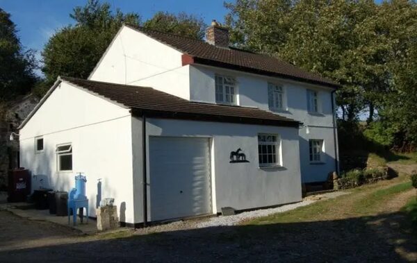 A white rendered rural house with garage, oil tank and external pump equipment outside