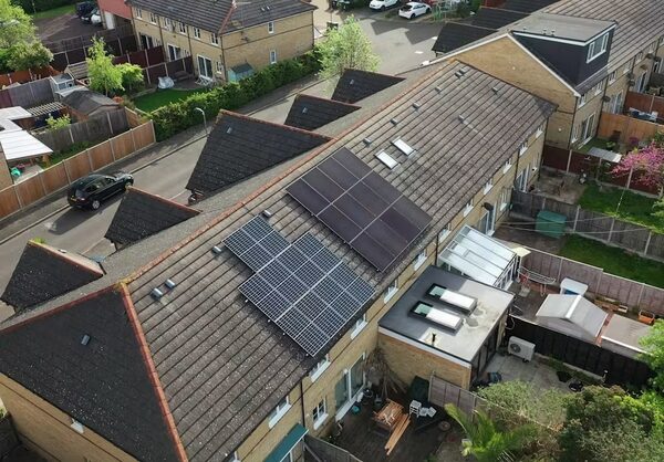Aerial view of solar panels installed on the tiled roofs of neighbouring terraced houses on a UK residential street