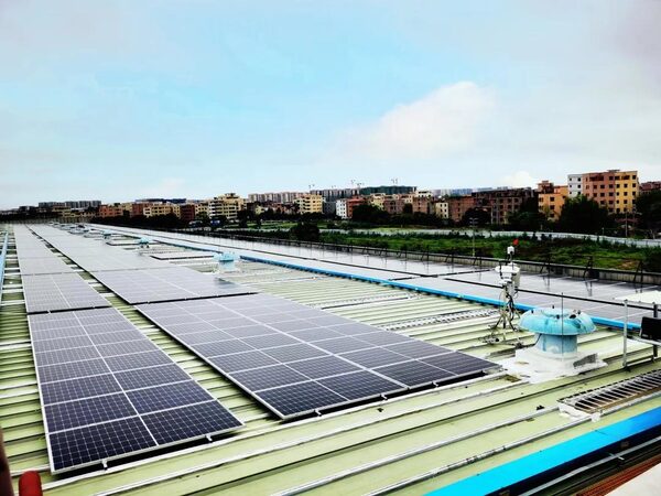 Rows of solar panels installed on a large industrial rooftop with buildings in the background