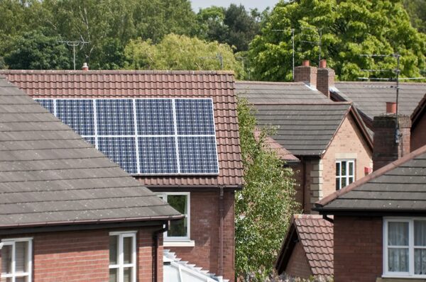 Solar panels installed on the tiled roof of a brick house in a residential neighbourhood