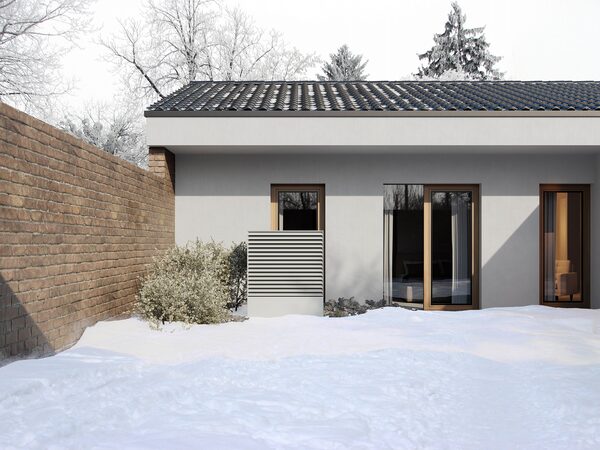 An air source heat pump unit installed outside a modern house in a snowy garden