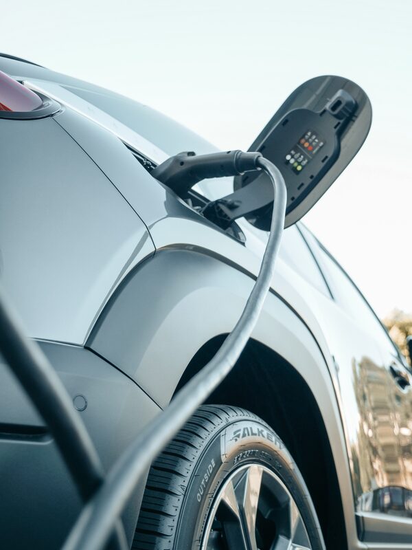 A close-up of an electric car with a charging cable plugged into its charging port