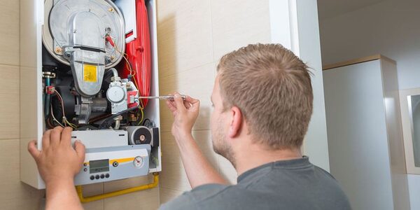 A technician servicing the internal components of a wall-mounted gas boiler in a home