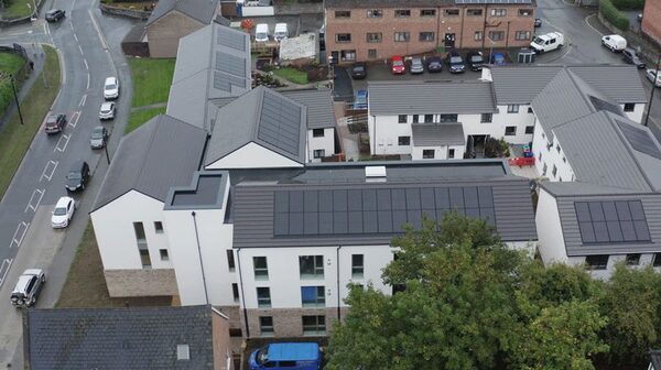 Aerial view of a housing development in Welshpool with solar PV panels on the roofs of new-build flats and existing homes