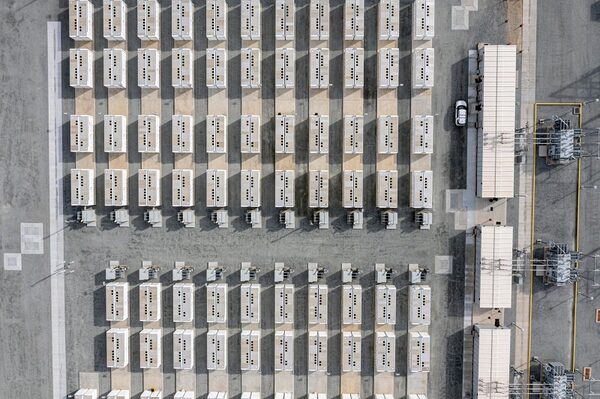 Aerial view of a large grid-scale battery storage facility with rows of white battery containers and electrical equipment